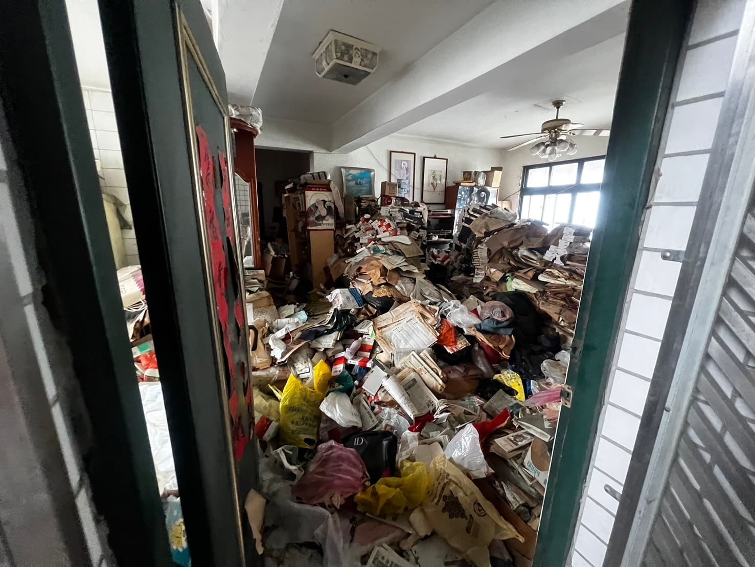 透過鐵窗望入屋內地板堆滿書報雜物,搬家垃圾清運廢棄物處理大型清空需求