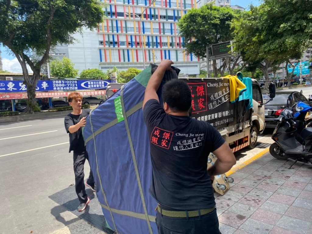 成傑搬家工作人員在路旁合力扶穩以搬運毯及束帶包覆的大型家具,家庭搬家重型家具保護