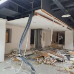 辦公室拆除工程天花板與隔間牆已拆除,地面堆滿廢棄板材,成傑搬家垃圾清運待處理現場