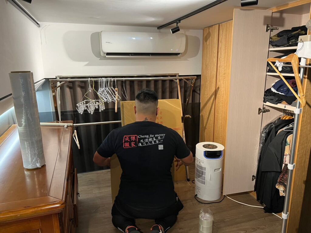 成傑搬家工人蹲在臥室整理空調除濕機旁物件，套房搬家打包作業準備現場