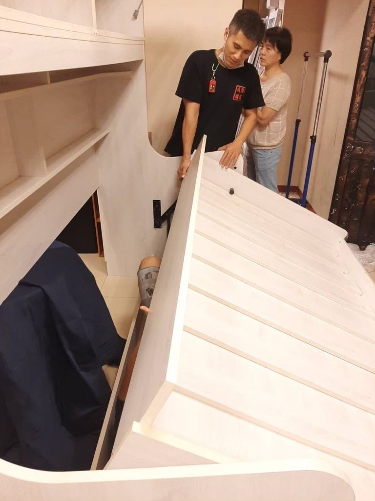 成傑搬家工作人員與客戶合力搬運白色大型系統衣櫃板材，代客搬家協力組裝定位