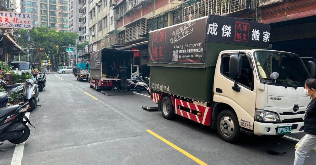 成傑搬家兩台大型貨車並排停於住宅街道，工作人員開啟車廂準備卸貨，家庭搬家到府服務