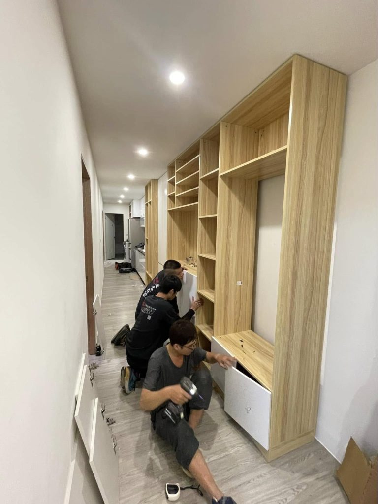 成傑搬家兩名工作人員跪地合力組裝高大原木色系統書牆,代客搬家入住後組裝服務