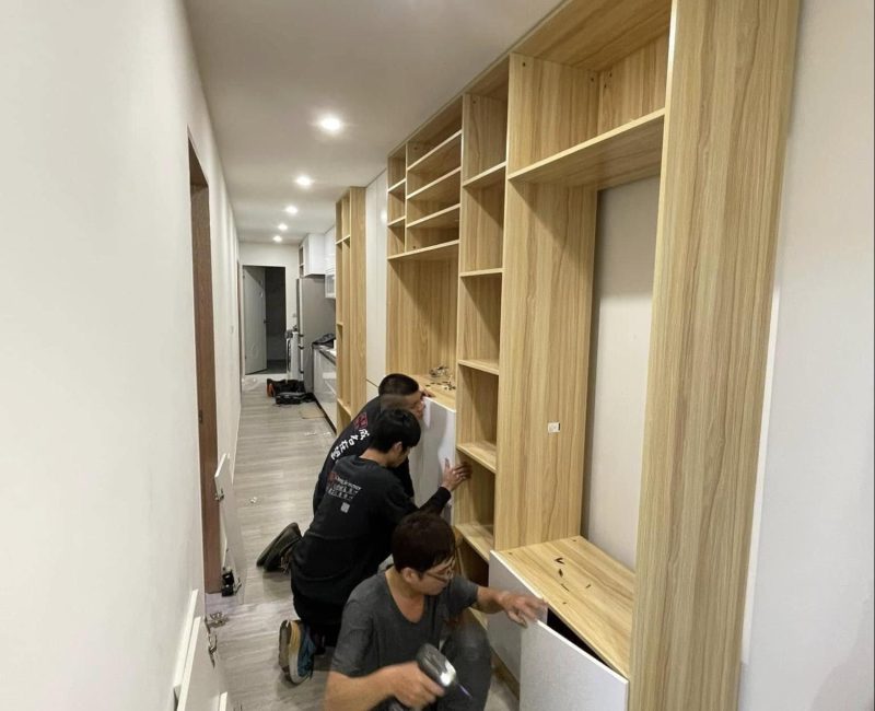 成傑搬家兩名工作人員跪地合力組裝高大原木色系統書牆，代客搬家入住後組裝服務